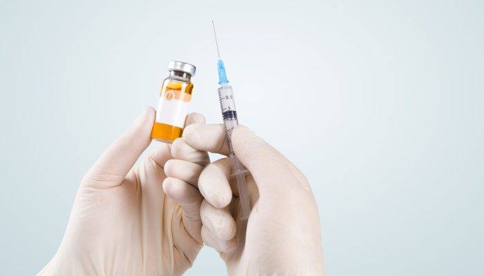 vecteezy_hand-holding-syringe-with-vaccine-against-corona-virus_6544089_322-scaled.jpg